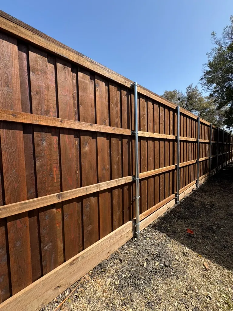 Framing side of a board-on-board cedar fence showing rails and posts