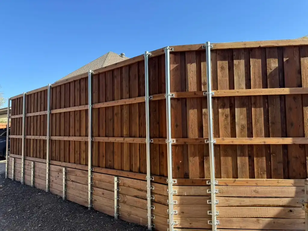 Back side of a custom cedar fence showing the retaining wall and post framing