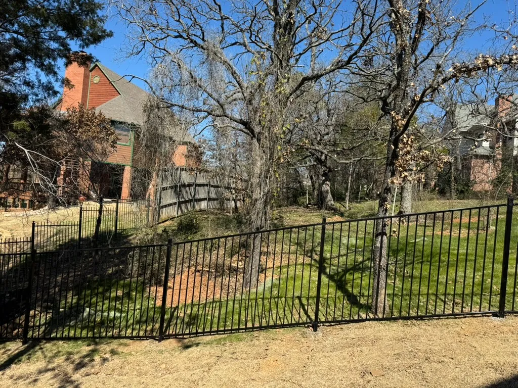 Black flat-top iron fence stepped down a wooded hillside