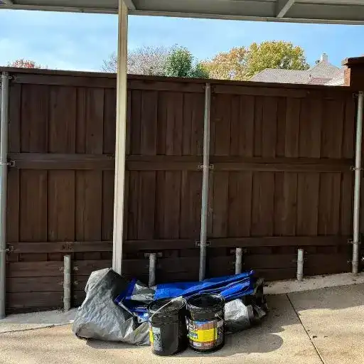 Wood Defender stain buckets on site in front of a freshly stained fence