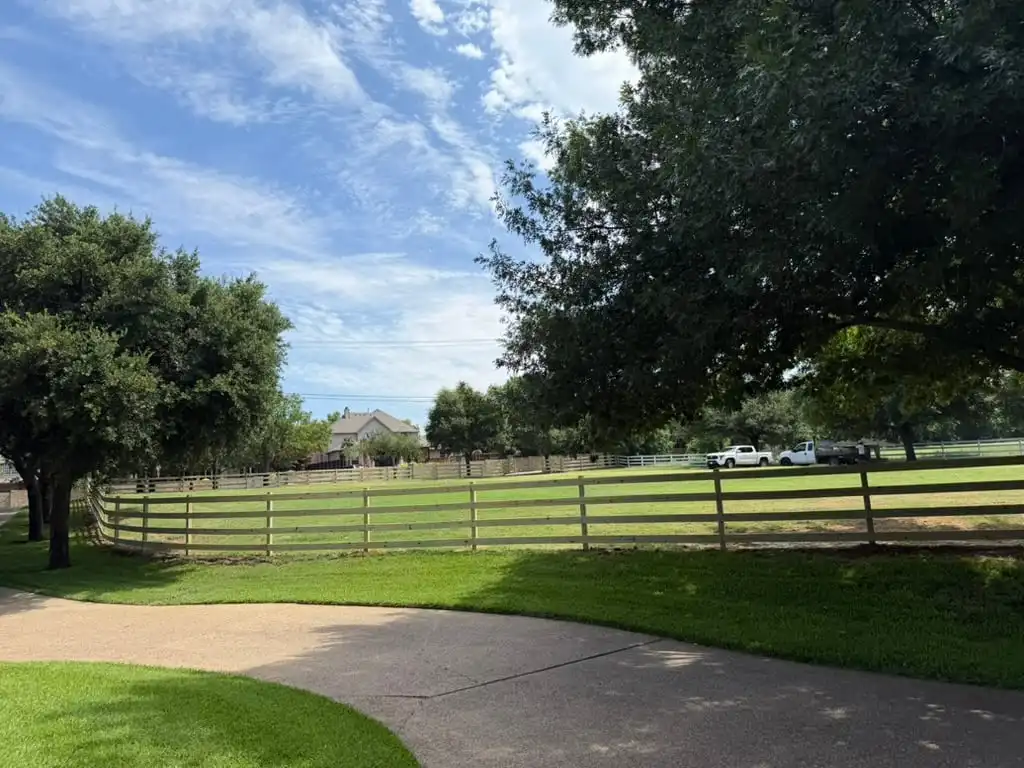 Four rail ranch fence curving around a North Texas estate lawn