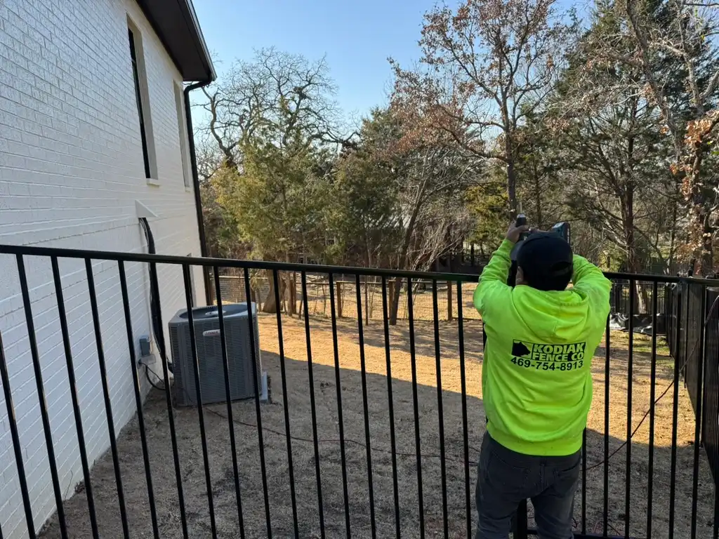 Certified Kodiak installer welding an ornamental iron fence on site