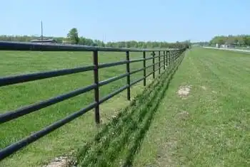 Multi-rail pipe fence running along open pasture
