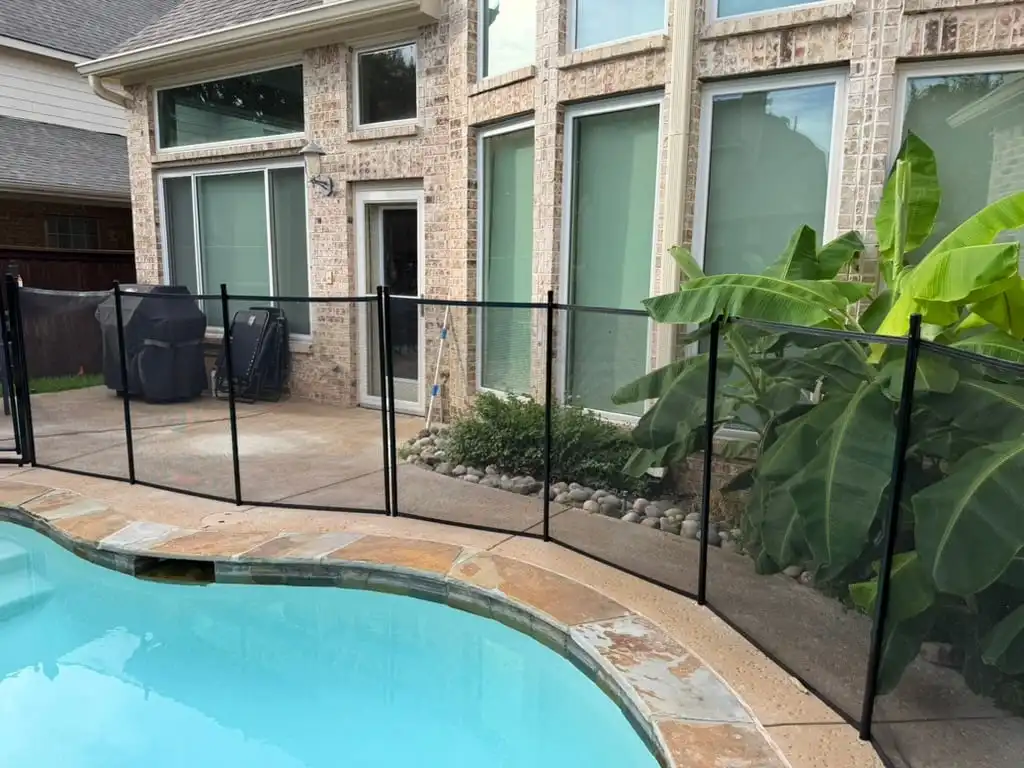 Removable black mesh pool fence installed around a backyard pool