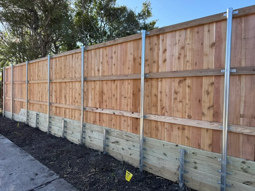 Wood retaining wall rebuilt beneath a replaced privacy fence